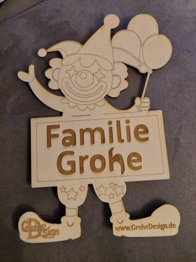 Bunter Clown mit individueller Aufschrift Holzfigur eines Clowns hält ein Schild mit der Aufschrift "Familie Grohe".